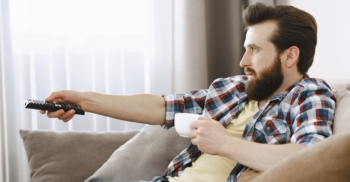 Mann i sofaen hjemme i Norge sjekker fjernkontrollen etter en iptv-innloggingsfeil
