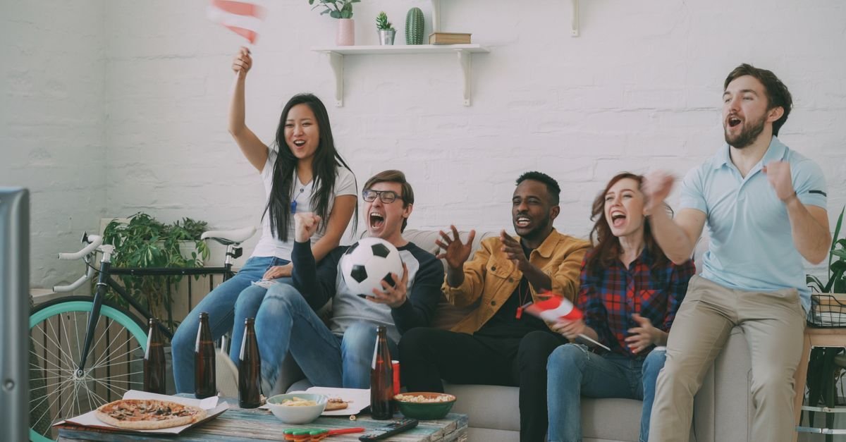 Venner jubler i sofaen mens de ser direktesendt sport via iptv