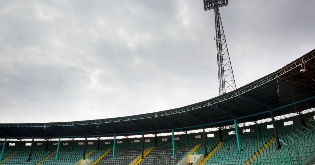 Folksomt fotballstadion under en kveldskamp i mesterskapet