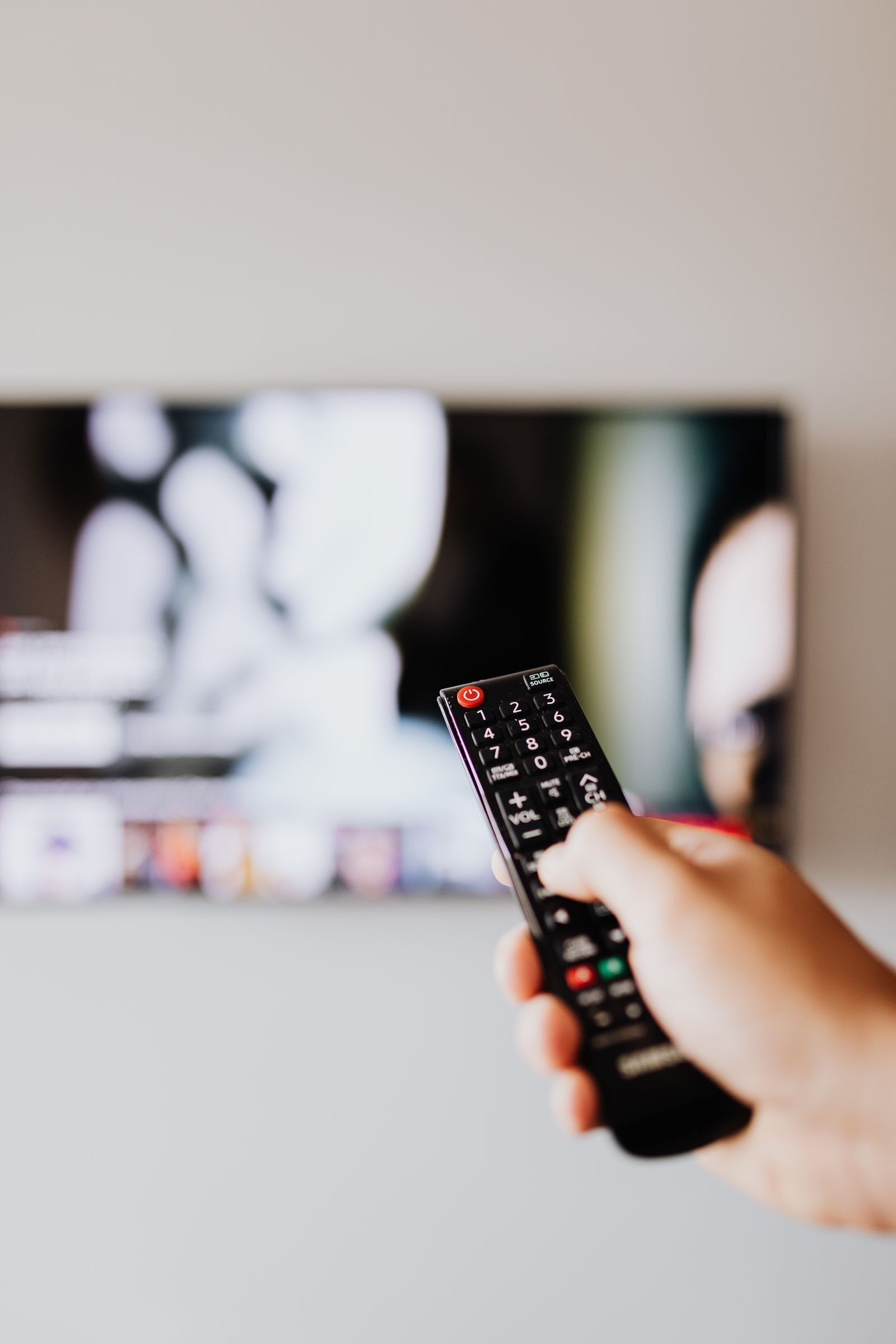 Fjernkontroll pekt mot en tv mens man sammenligner iptv-tjenester