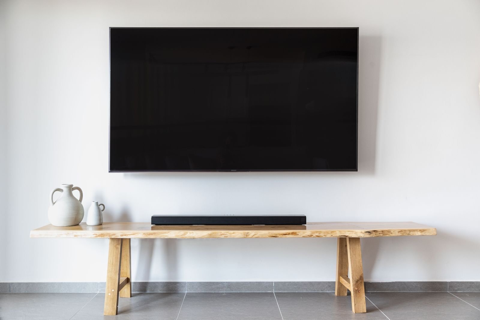 Veggmontert flatskjerm-tv over en trekonsoll i et lyst nordisk rom