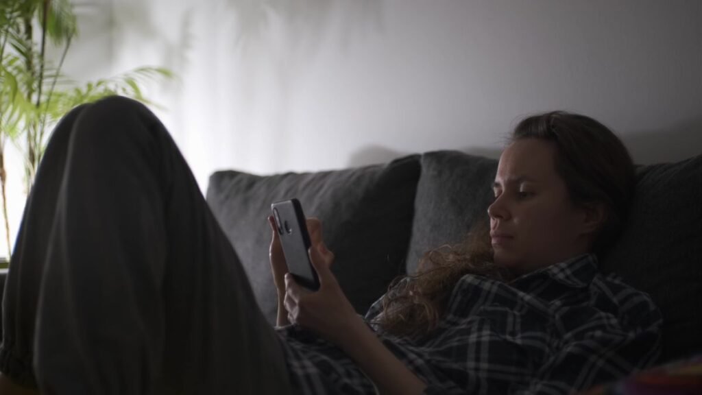 Kvinne i sofaen leser et norsk iptv-forum på mobilen