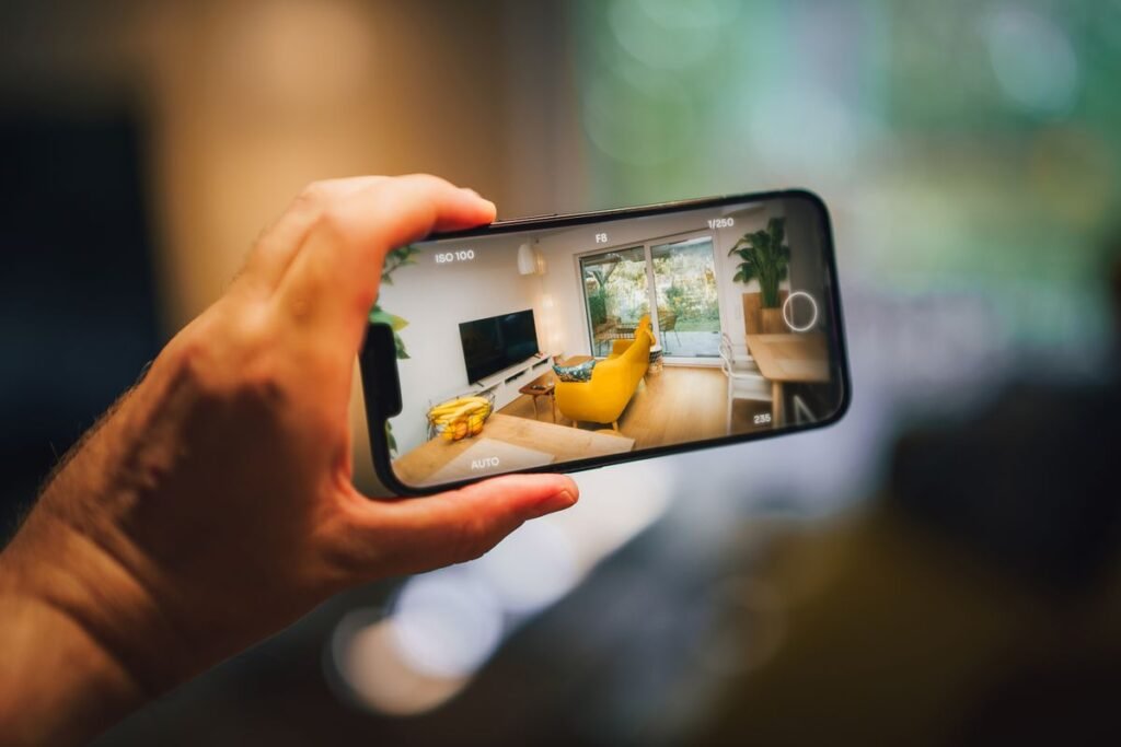 Hånd med mobil som fotograferer skjermen, slik noterer du MAC-adressen for set iptv